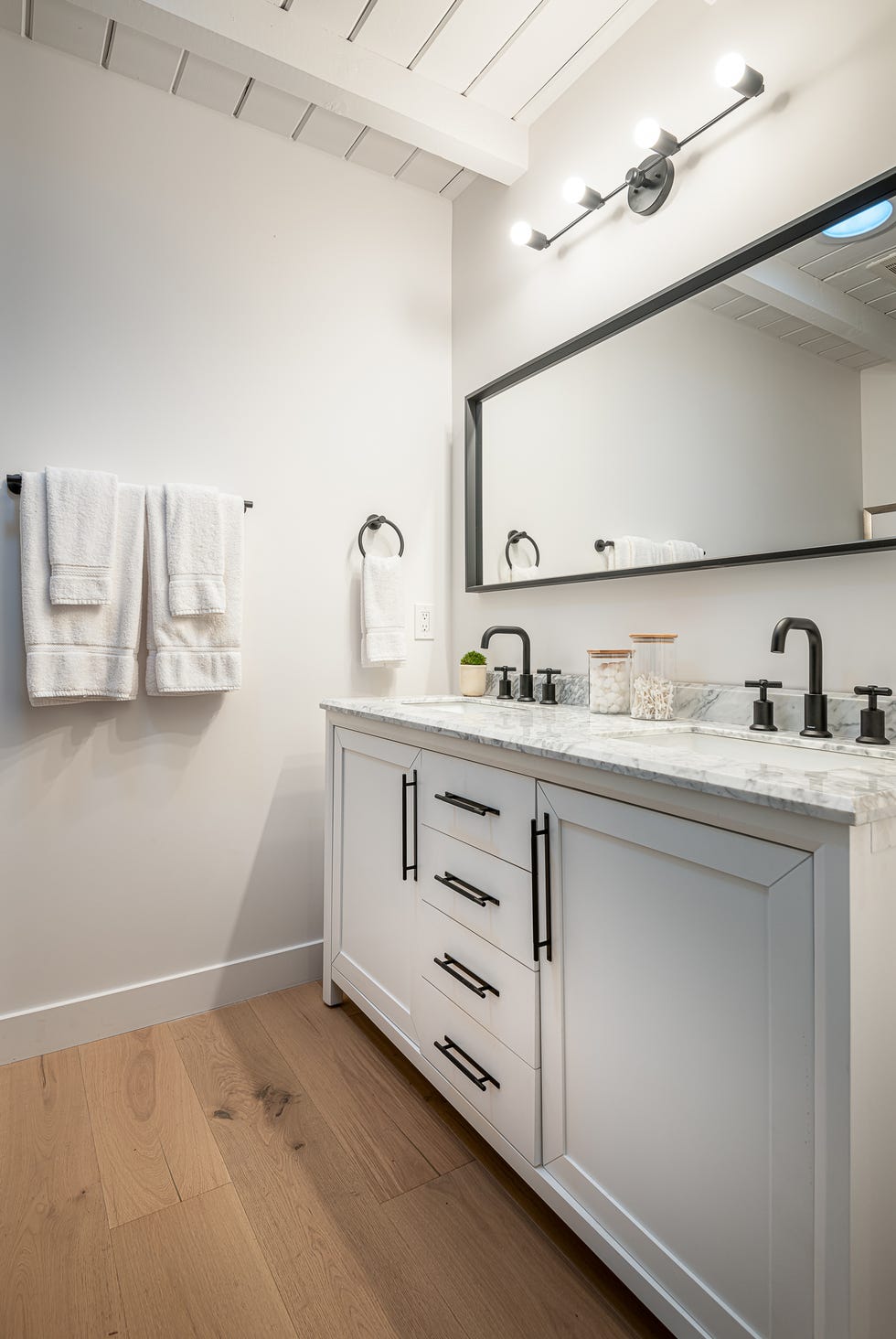 baño moderno con mueble blanco, encimera de mármol y dos lavabos con grifos negros de acabado mate
