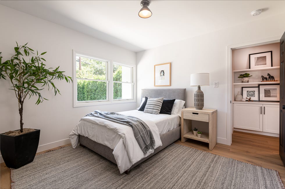 dormitorio con cama y cabecero tapizados en gris y alfombra de rayas