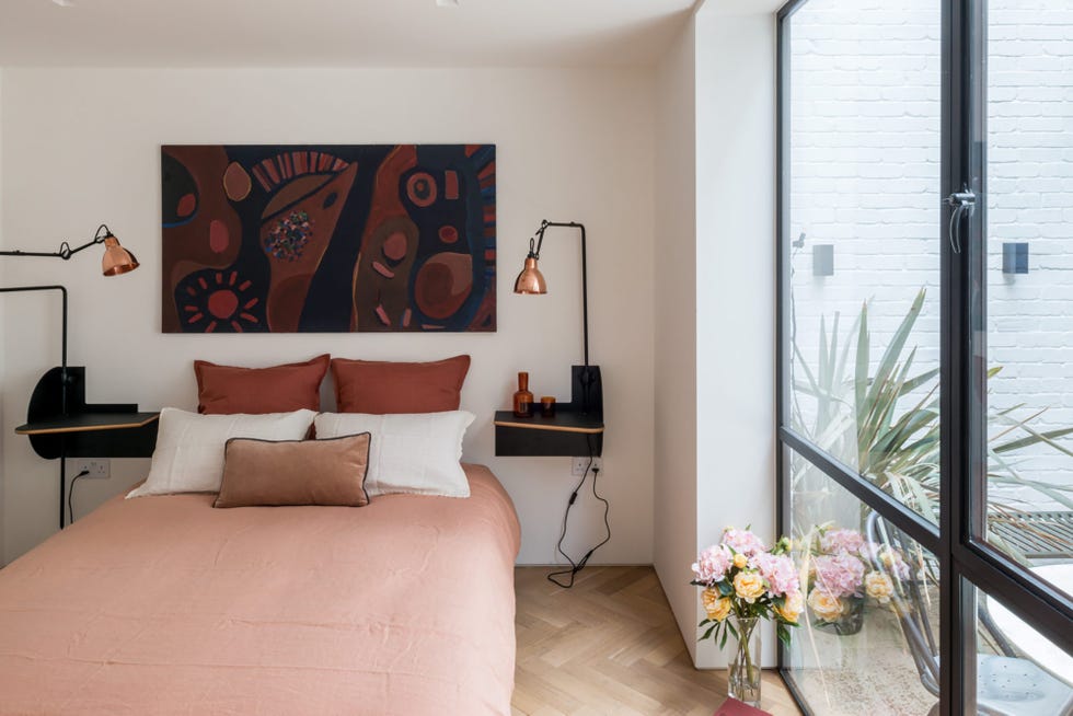 ropa de cama en colores empolvados y lámparas de mesa de estilo industrial con pantallas de cobre