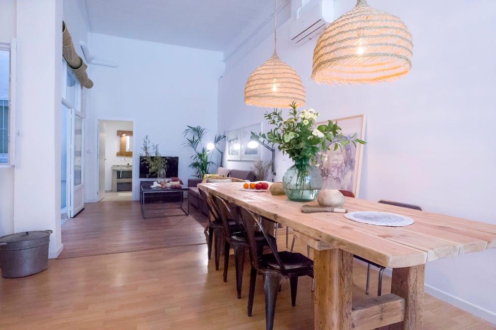 comedor abierto con mesa de madera raw, sillas de metal y lámparas de fibras