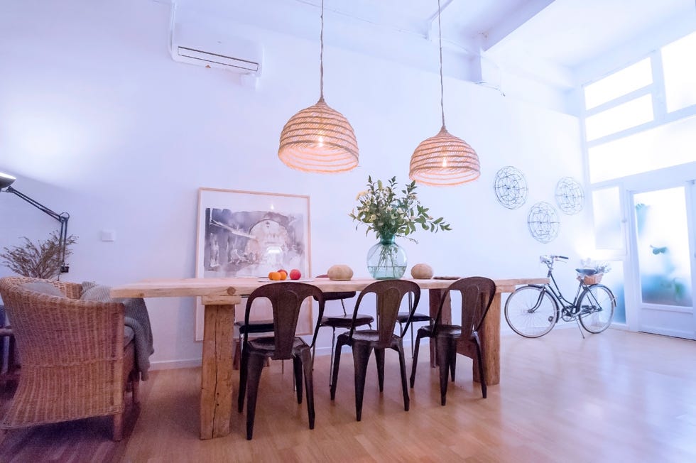 comedor con mesa de madera raw, sillas de metal y lámparas de fibras