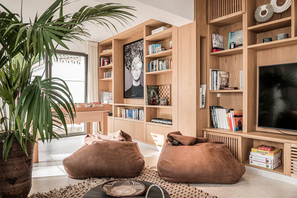 salón con estantería de madera y pufs de ante marrón