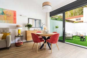 mesa de comedor redonda con sillas tapizadas en rojo y acceso a la terraza