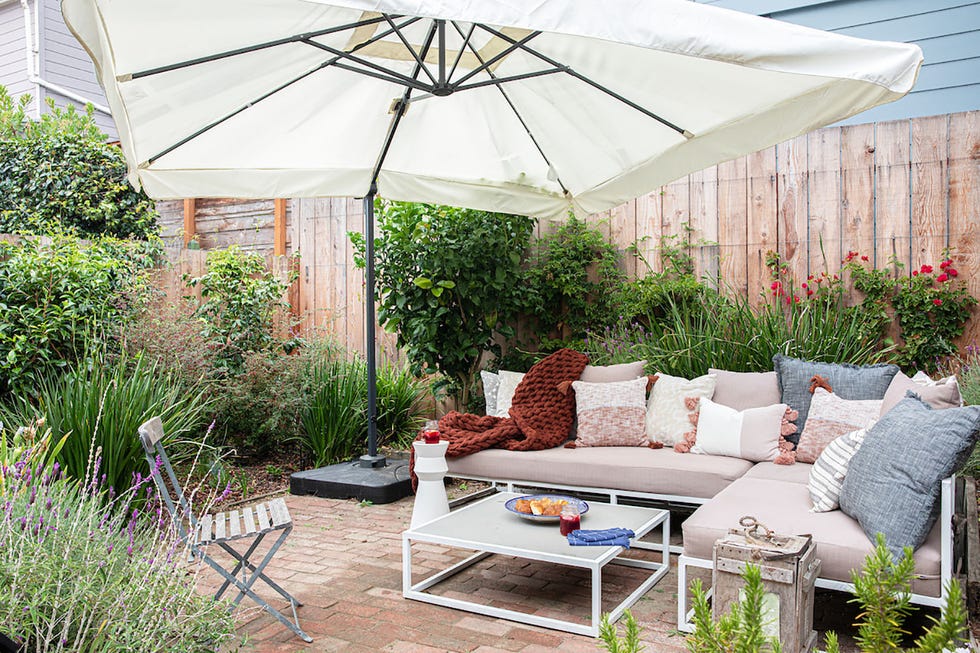 terraza con plantas, sofá en l y sombrilla