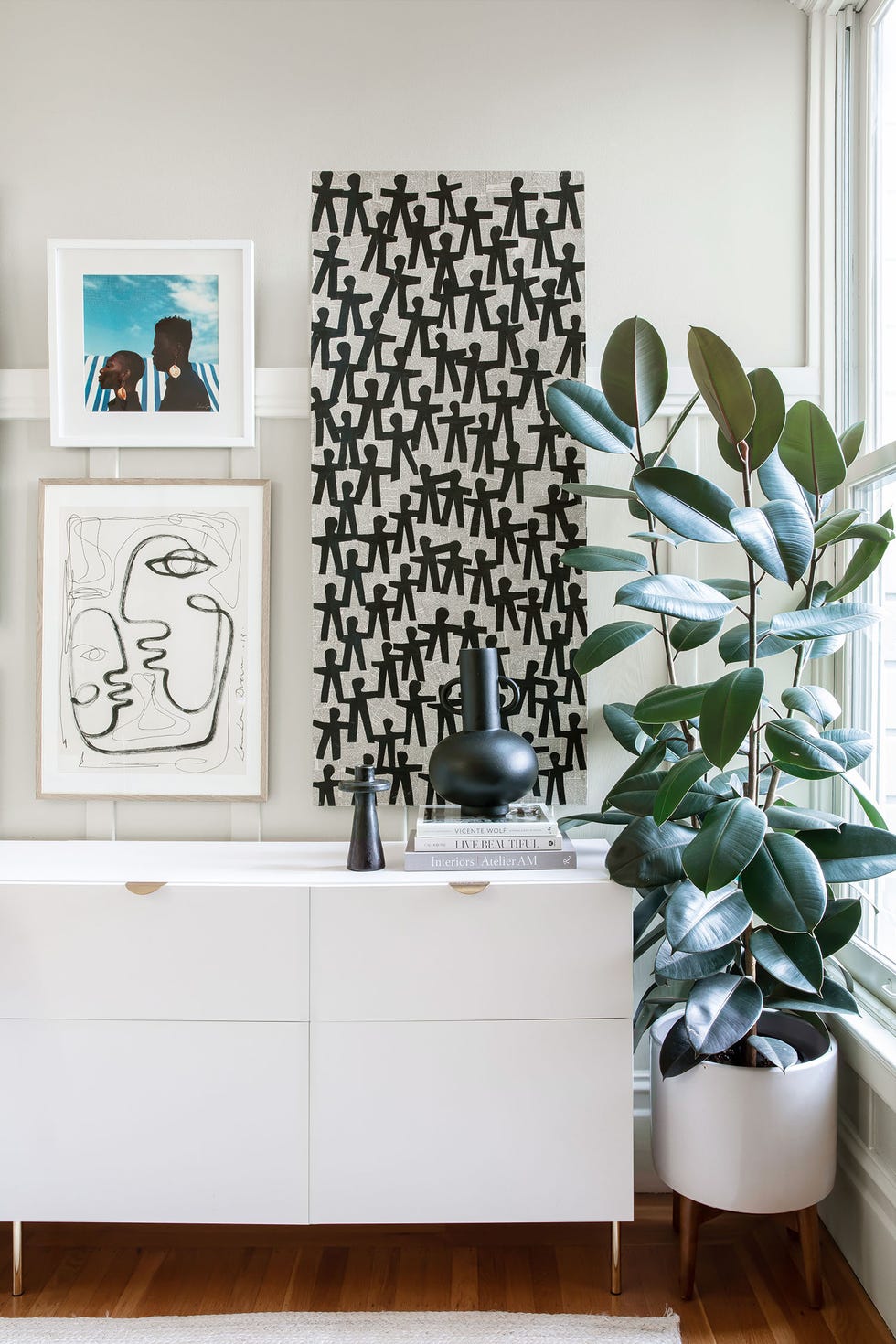aparador blanco moderno decorado con pinturas y un ficus