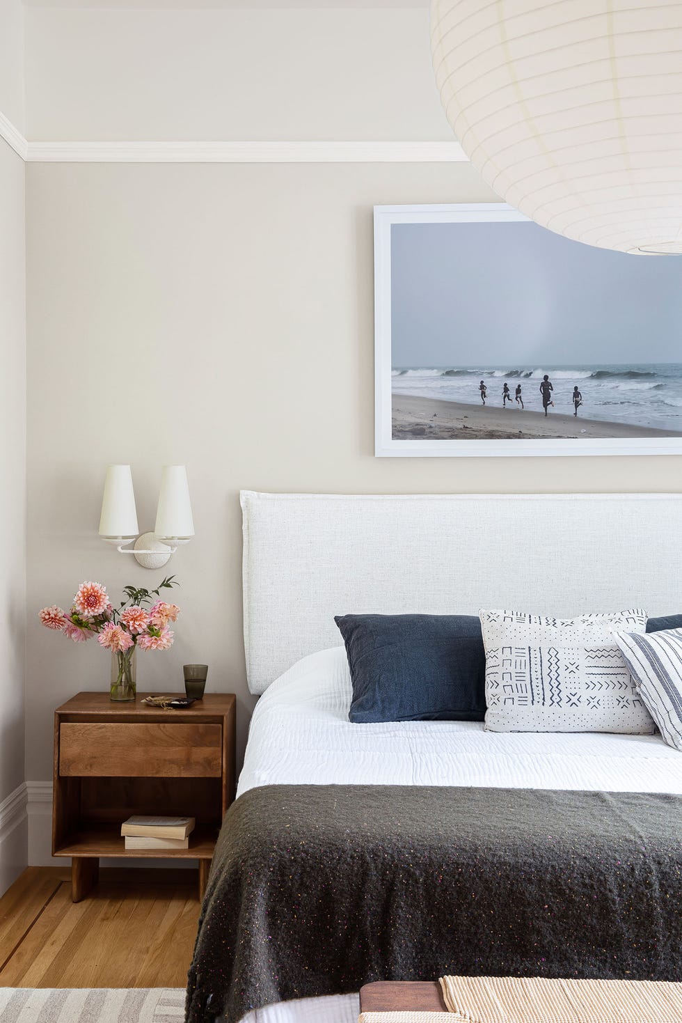 dormitorio con cabecero de lino blanco y fotografía de una playa sobre el cabecero