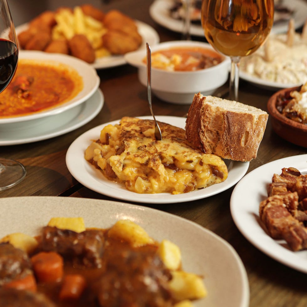 a spanish omelette served with a slice of bread and surrounded by other casa dani dishes