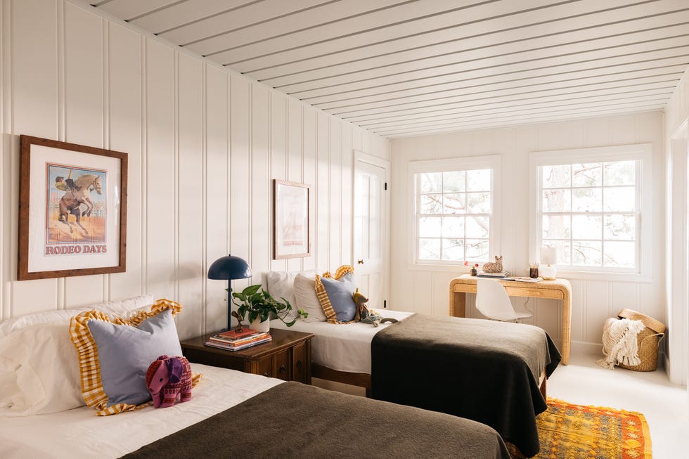 habitación con dos camas con techo y paredes revestidas de lamas de madera en color blanco
