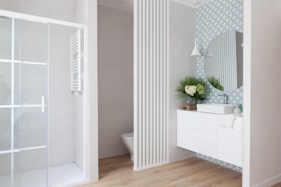 baño en suite con cabina de ducha, mueble volado blanco y papel pintado con motivos geométricos