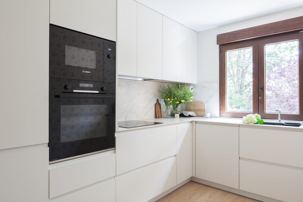cocina con armarios blancos con acabado mate sin tiradores y revestimiento efecto mármol