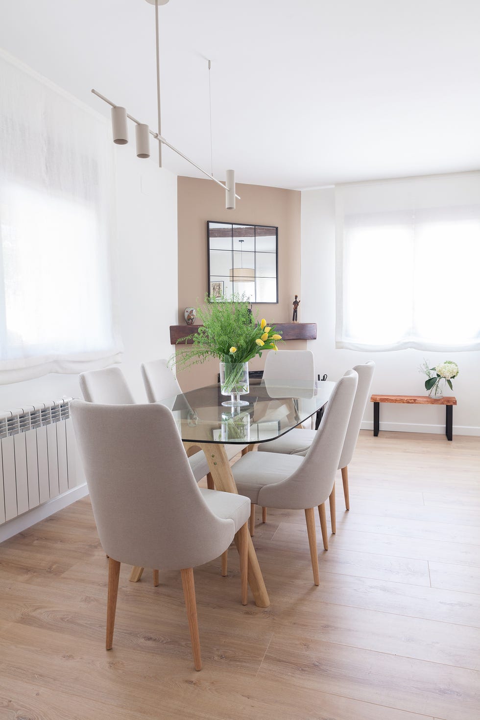 mesa de comedor de cristal con sillas grises y chimenea