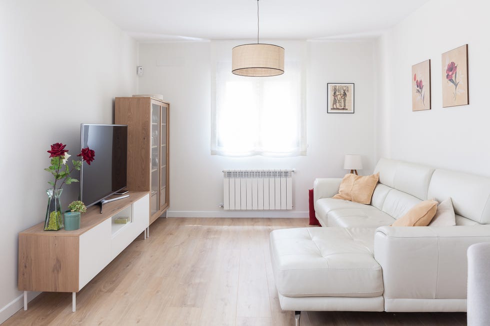salón con sofá con chaiselongue de piel blanca y mueble de tv junto a vitrina de diseño nórdico
