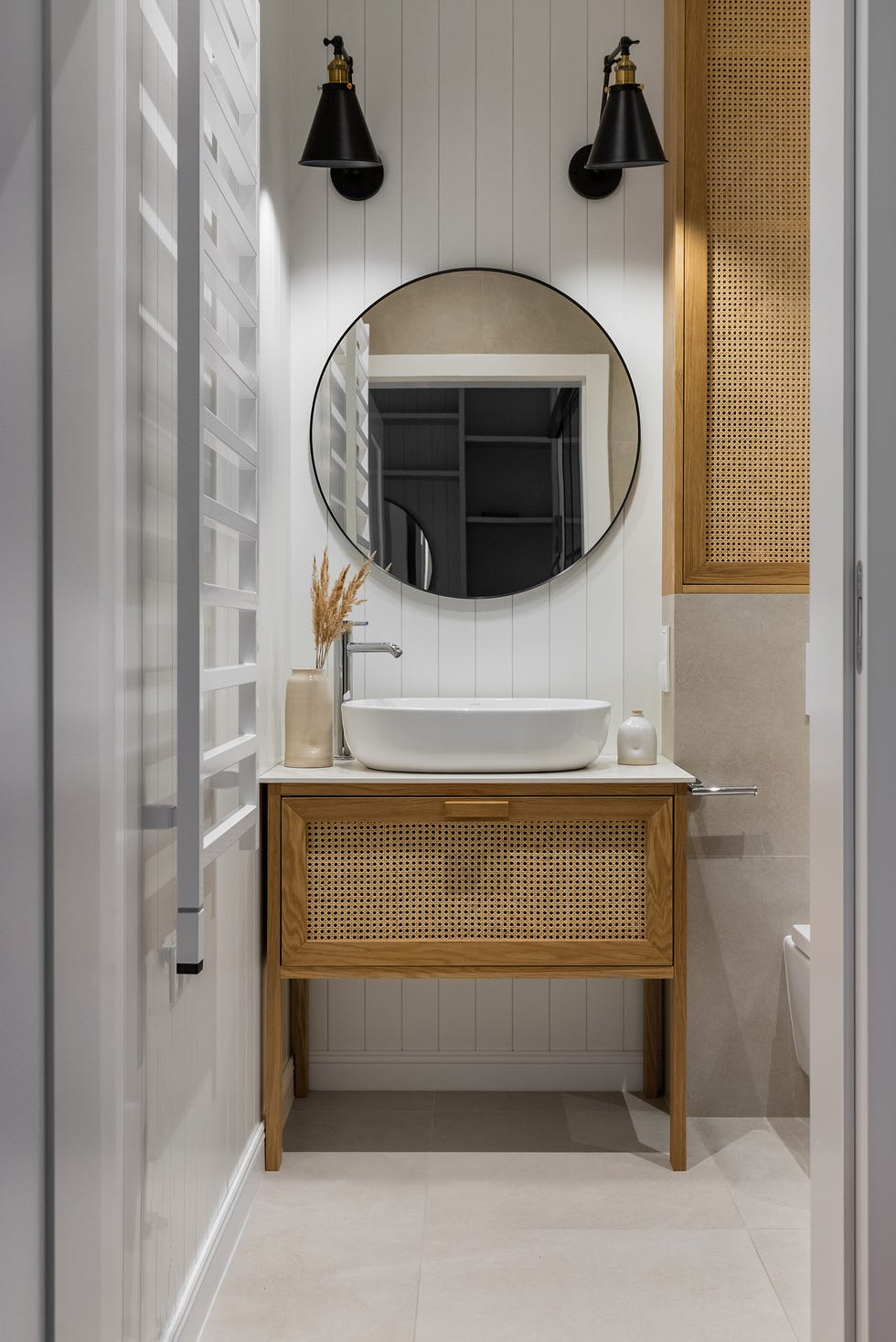 baño con mueble de madera y rejilla, lavabo exento y espejo redondo