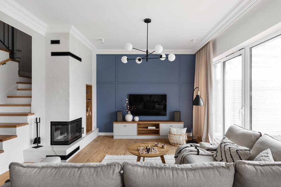 salón boho con sofá gris, pared azul y mueble de tv en blanco y madera