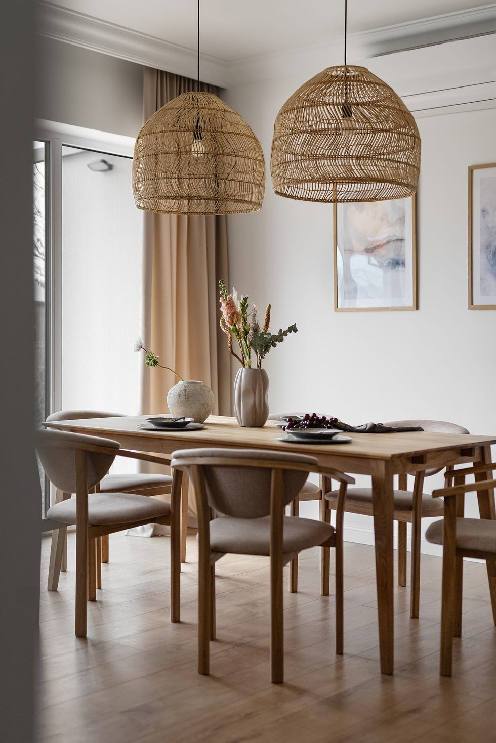 mesa de comedor de madera, sillas tipo wishbone y lámparas con pantallas de fibras
