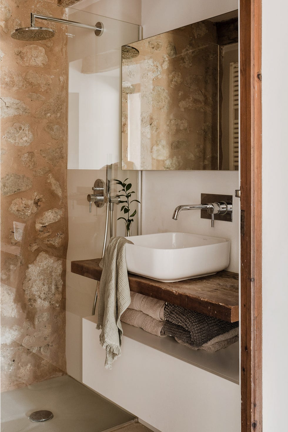 baño rústico con ducha y pared de piedra