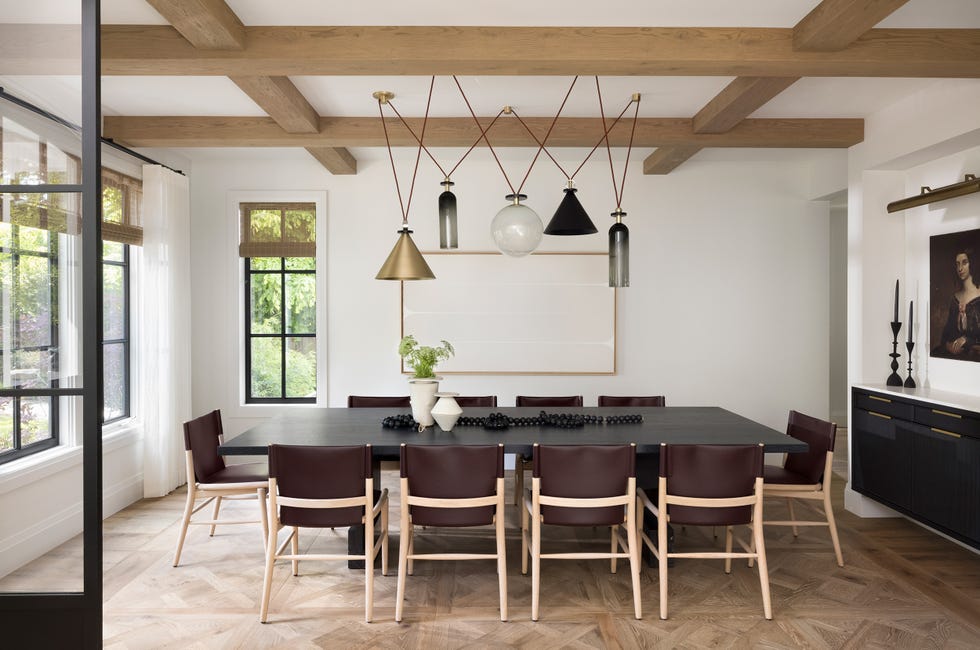 mesa de comedor de madera, sillas de piel burdeos y lámpara suspendida de latón