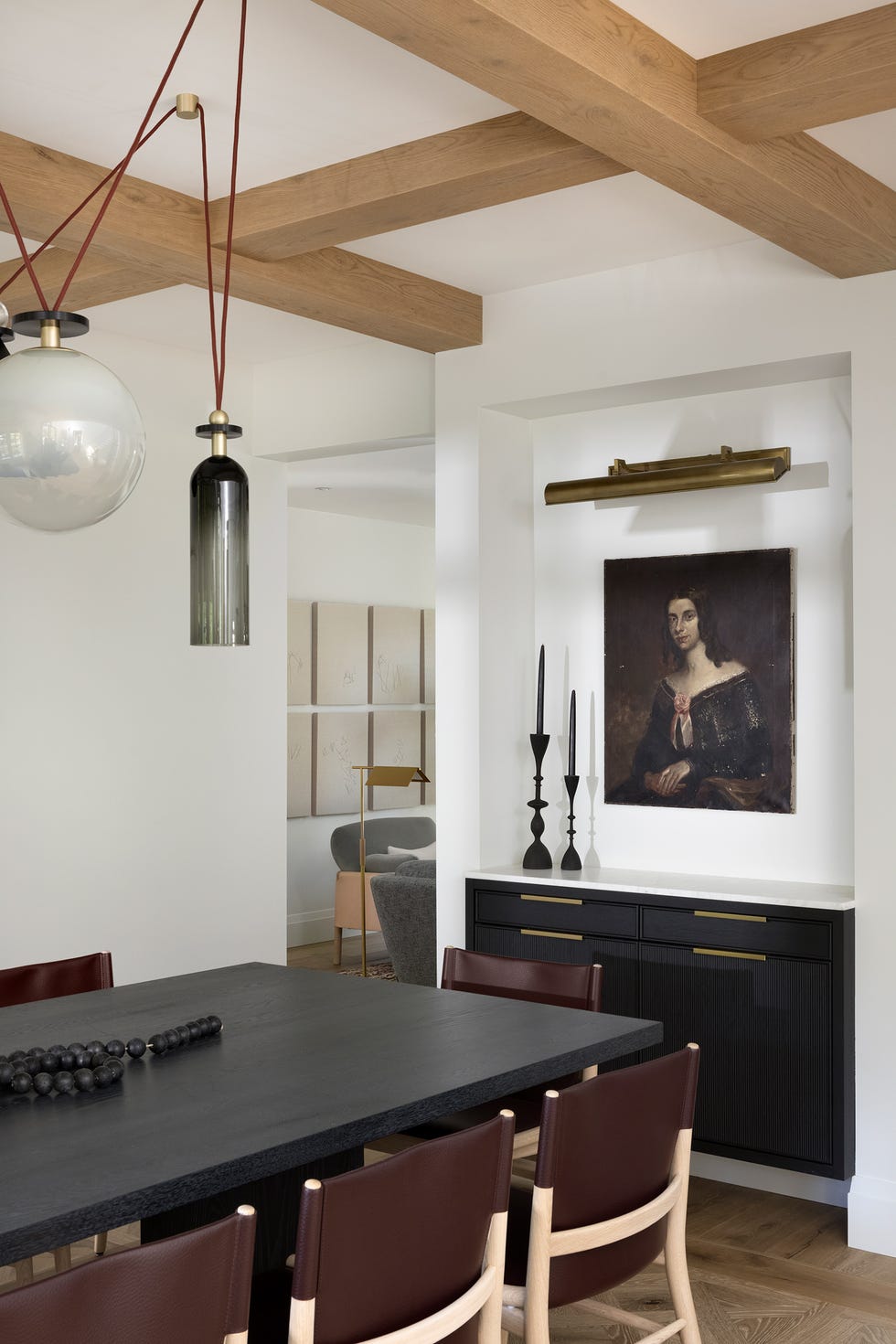 mesa de comedor de madera, sillas de piel burdeos y aparador de madera negra
