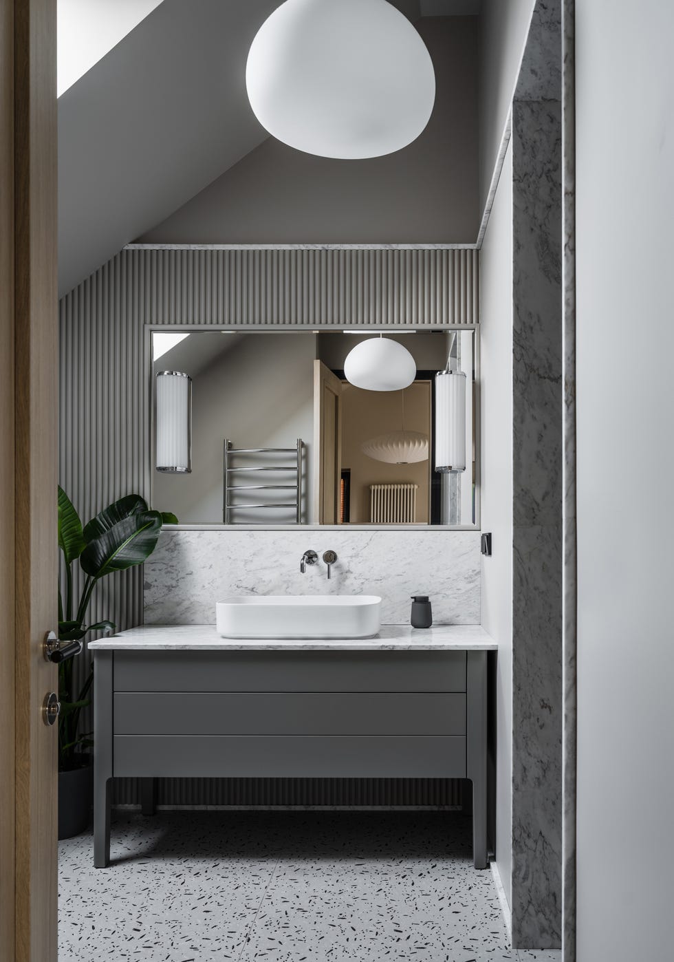 baño abuhardillado revestido con mármol y terrazo y mueble de color gris