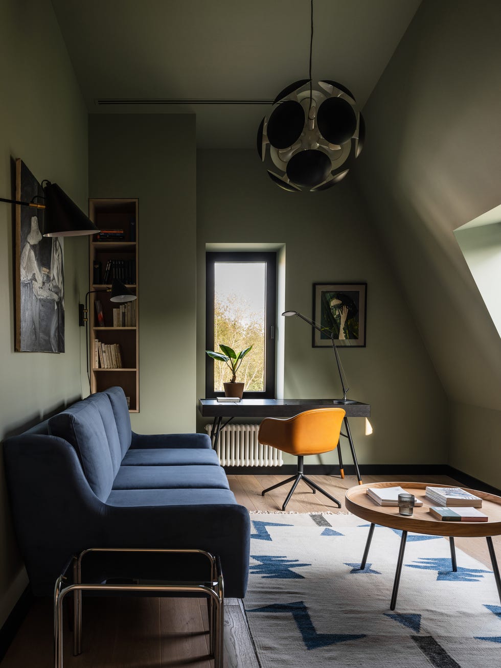 despacho con sofá cama de terciopelo azul y paredes verdes