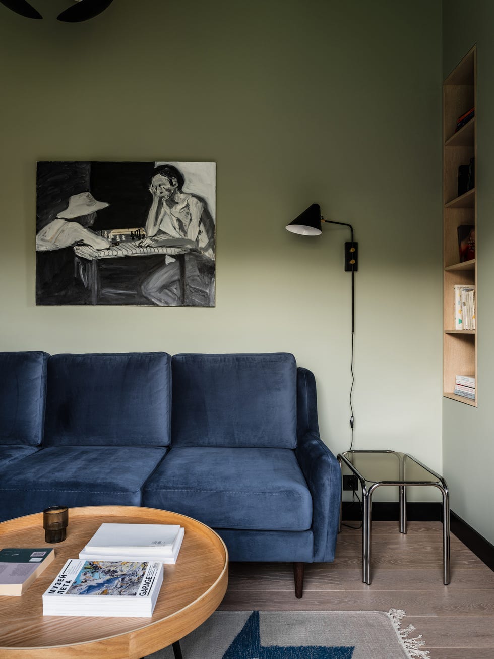 despacho con sofá cama de terciopelo azul y paredes verdes