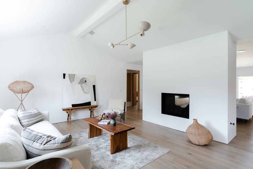 salón minimalista decorado en blanco con chimenea en muro de obra