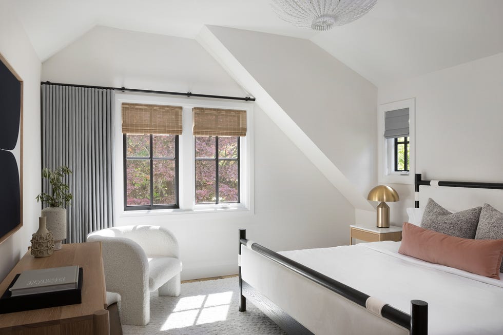 dormitorio blanco con cama de madera y butaca moderna con tapizado de borrreguito