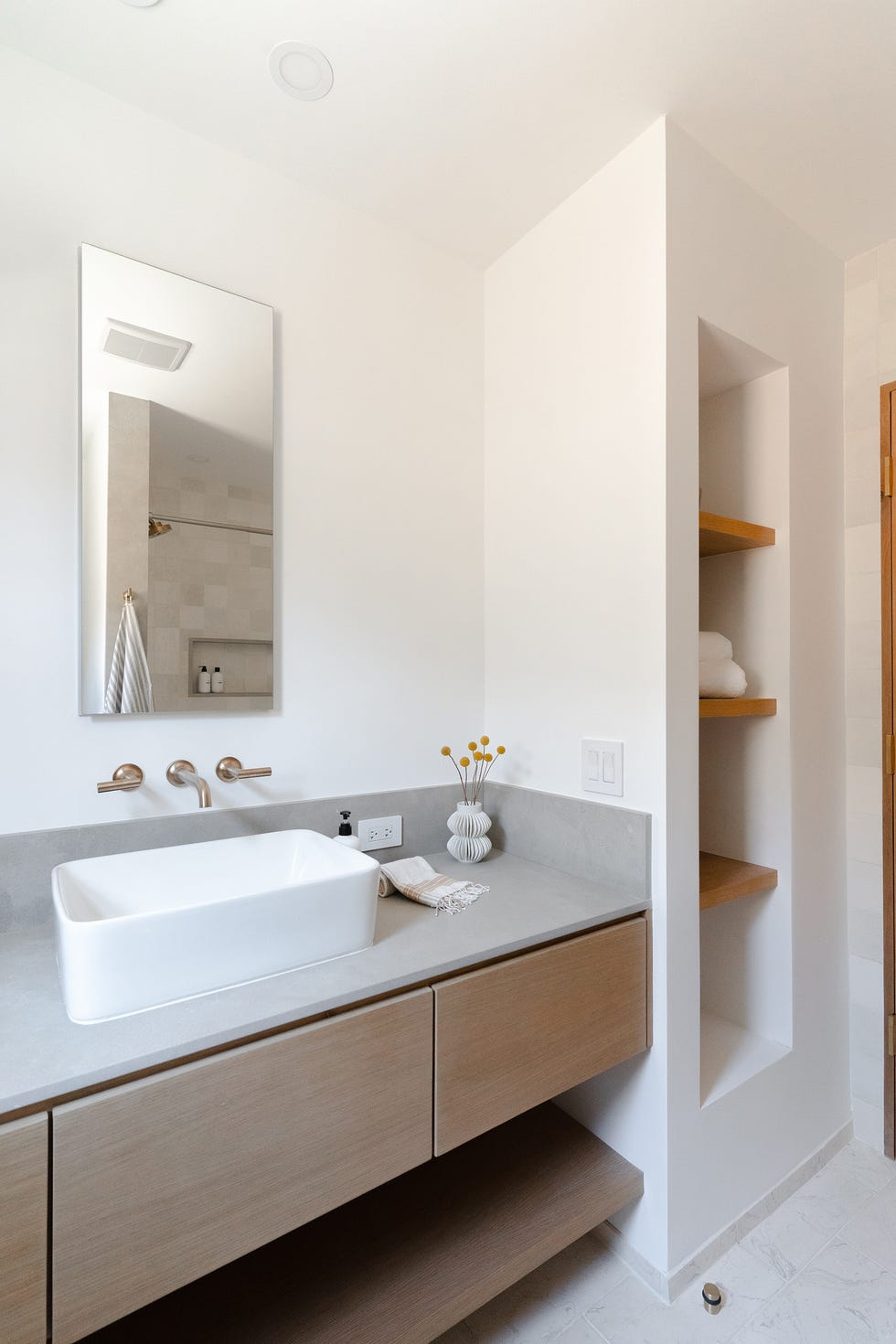 baño moderno con estantería de obra y mueble bajo lavabo suspendido con los frentes de madera