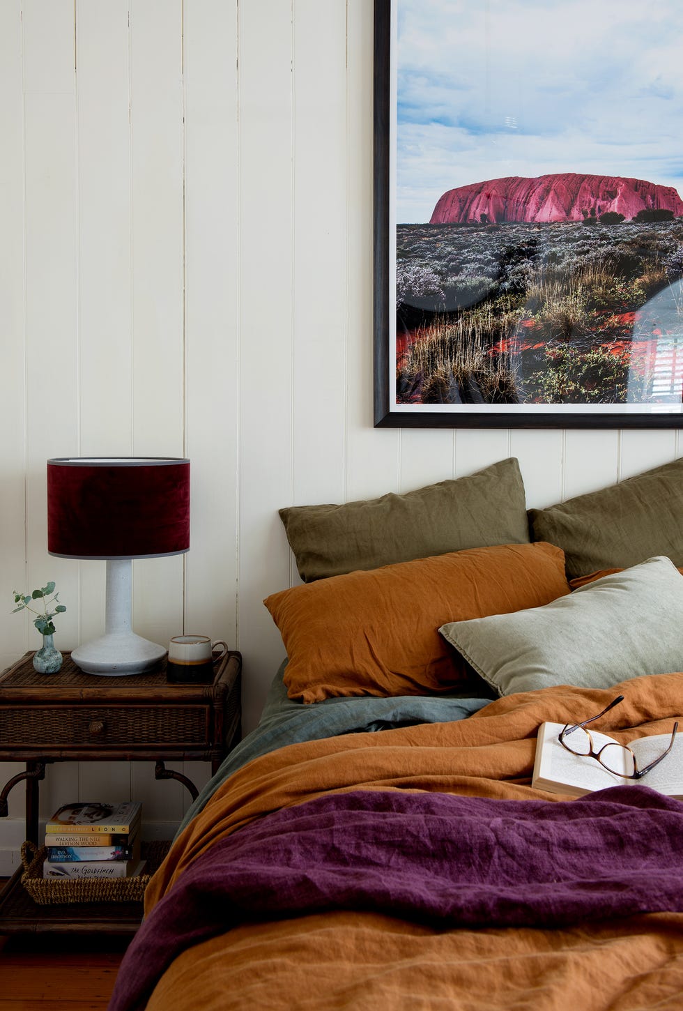 dormitorio de estilo rústico con lamas de madera blanca en las paredes y ropa de cama en tonos tierra