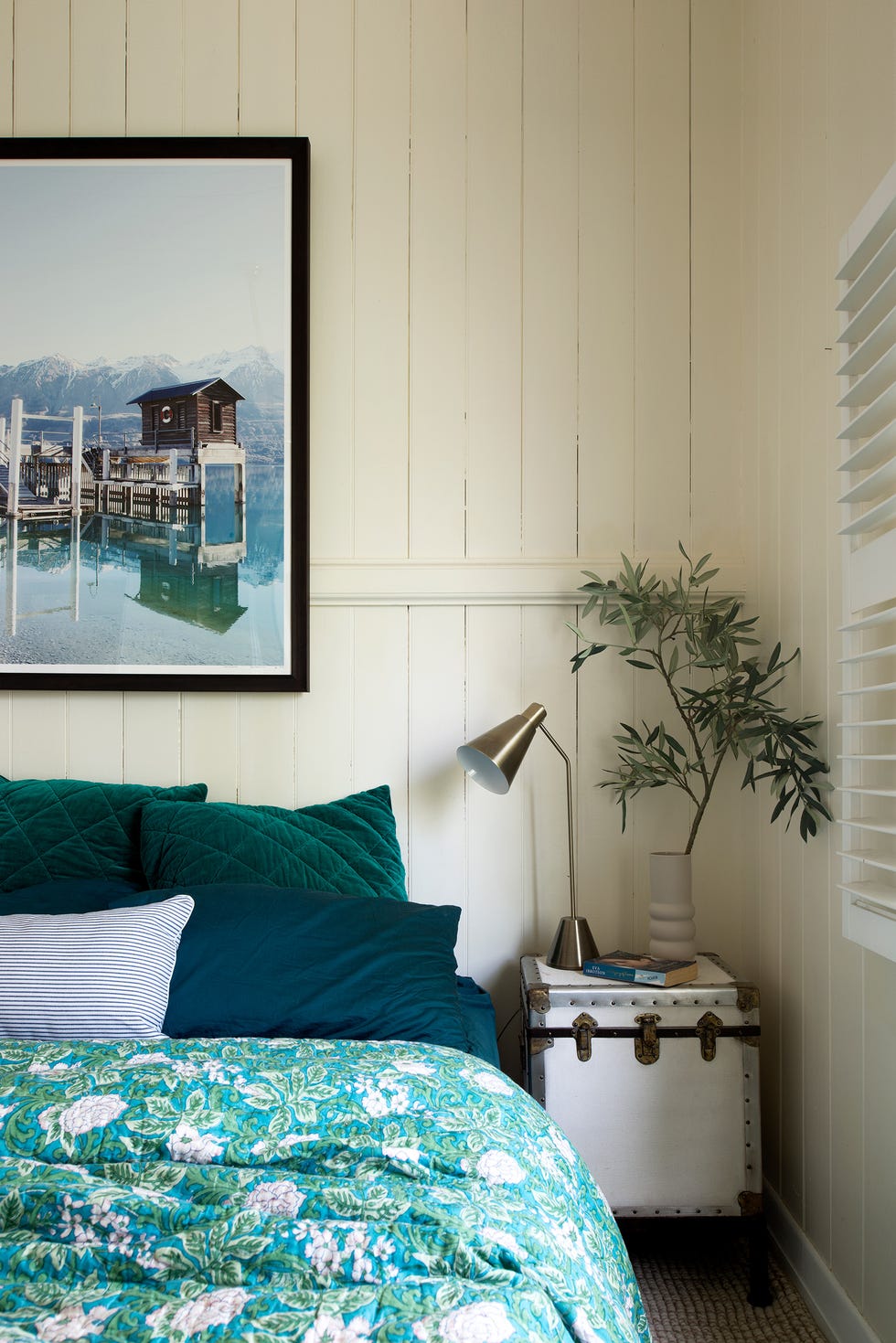 dormitorio de estilo rústico con lamas de madera blanca en las paredes y ropa de cama en tonos verdes y azules