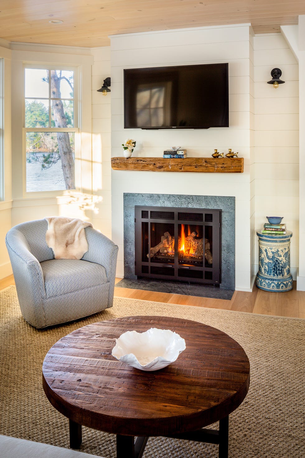 mesa baja redonda de madera, butaca y chimenea