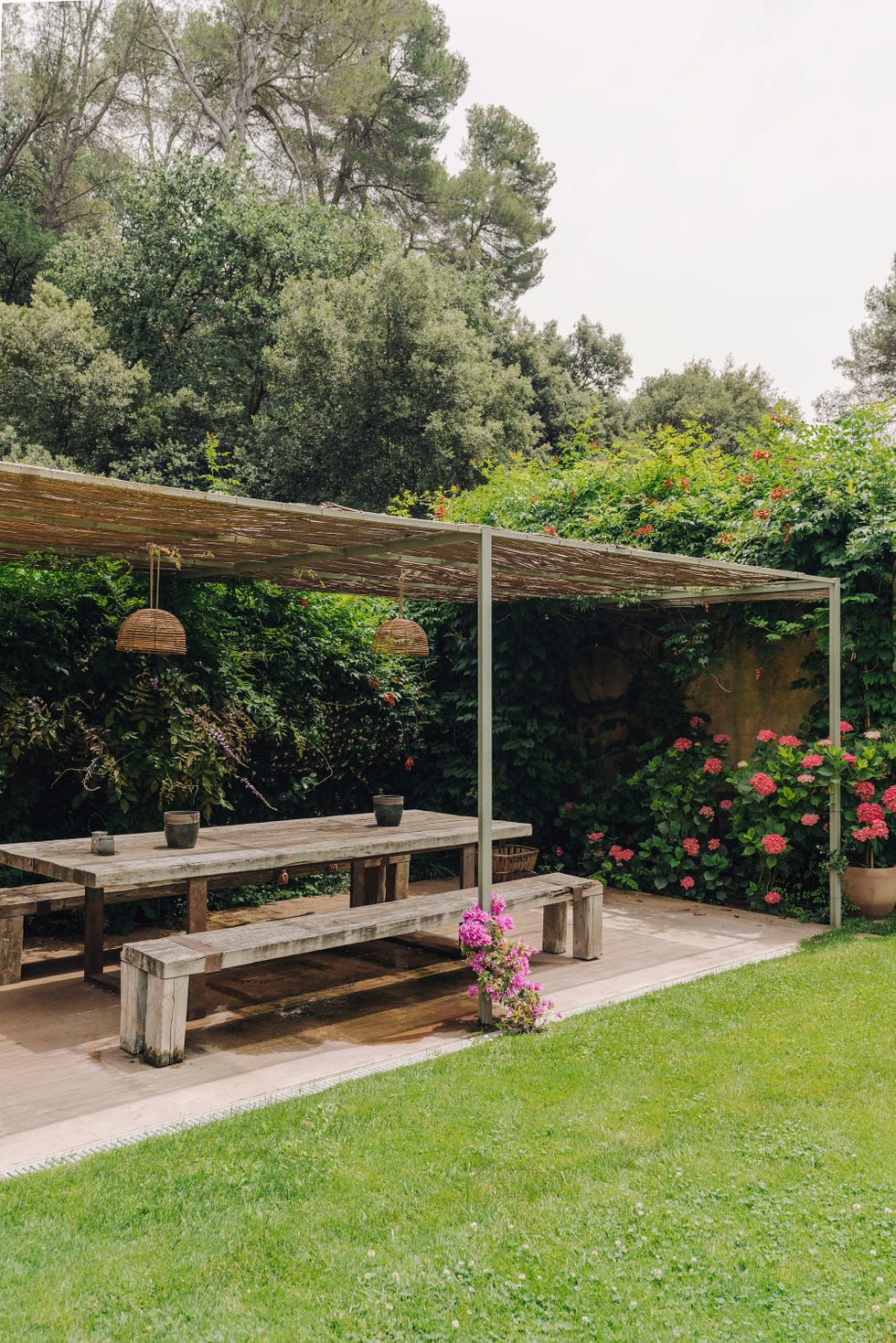 comedor exterior con mesa y bancos de madera bajo una pérgola