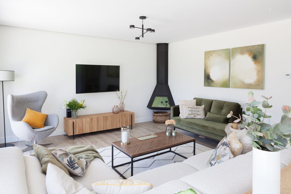 salón con chaiselongue de terciopelo verde, chimenea, mueble tv de madera y butaca orejera gris