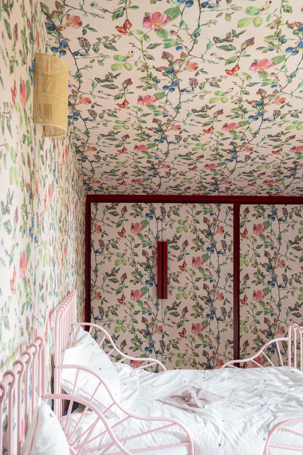 habitación infantil con papel pintado floral en techo y paredes