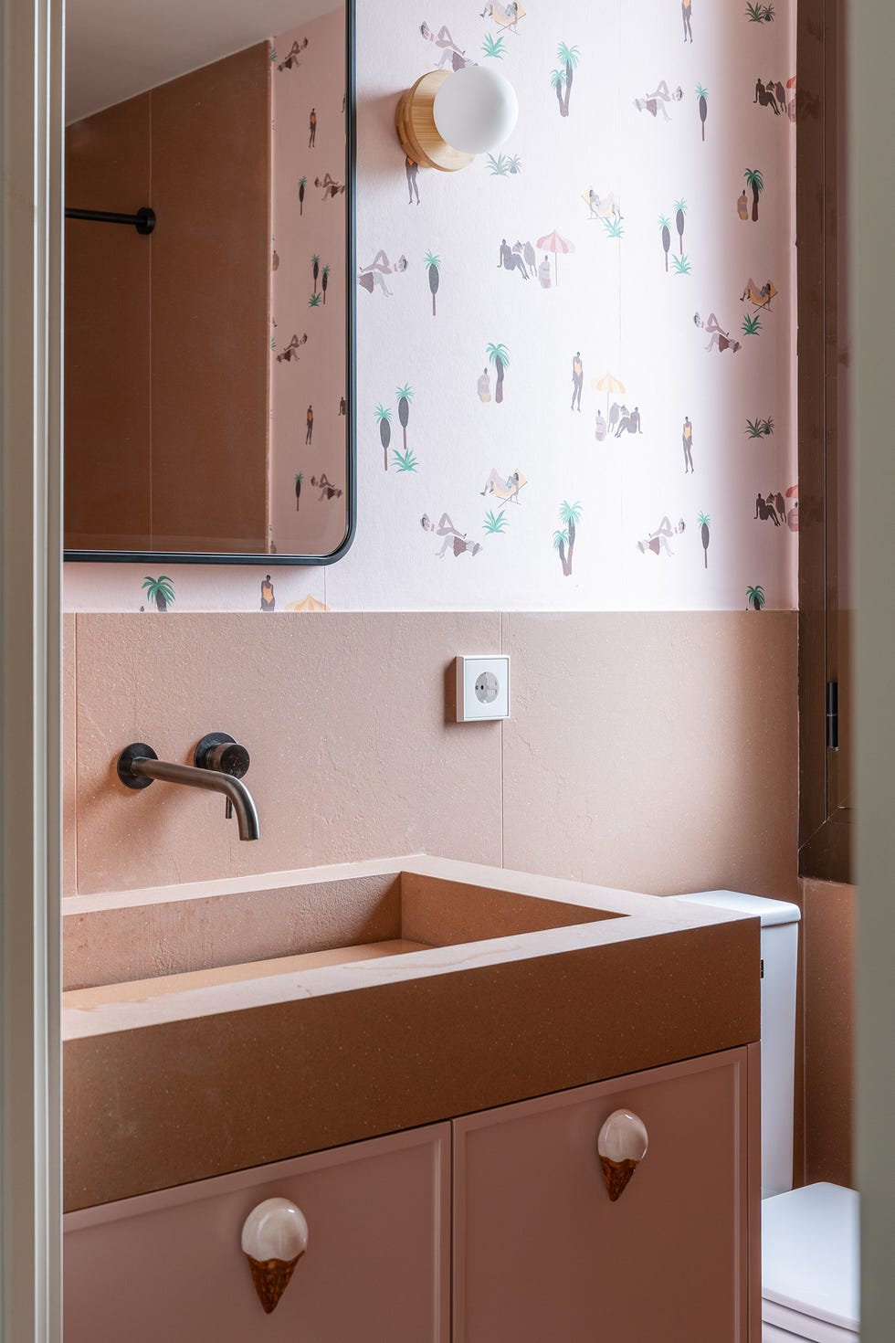 papel pintado con dibujos playeros y mueble de baño con tiradores en forma de helado bathroom with a mirror and a sink