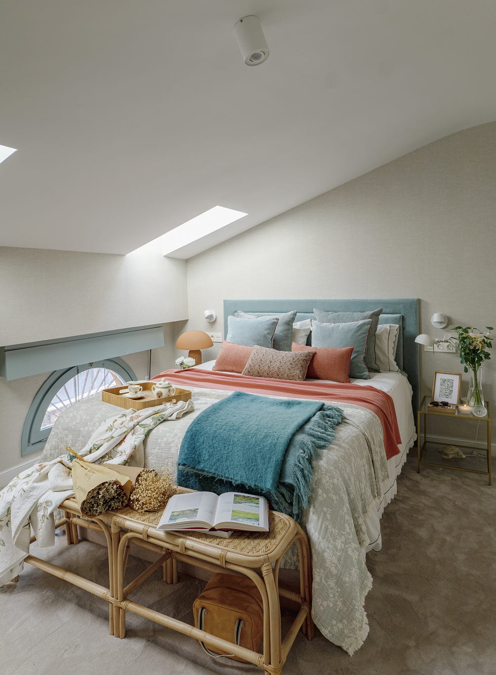 dormitorio con cabecero azul y banco de ratán a los pies de la cama