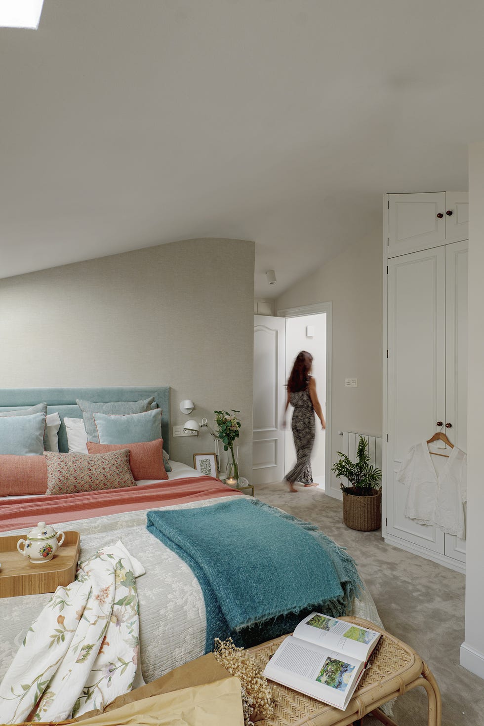dormitorio con cabecero azul y banco de ratán a los pies de la cama