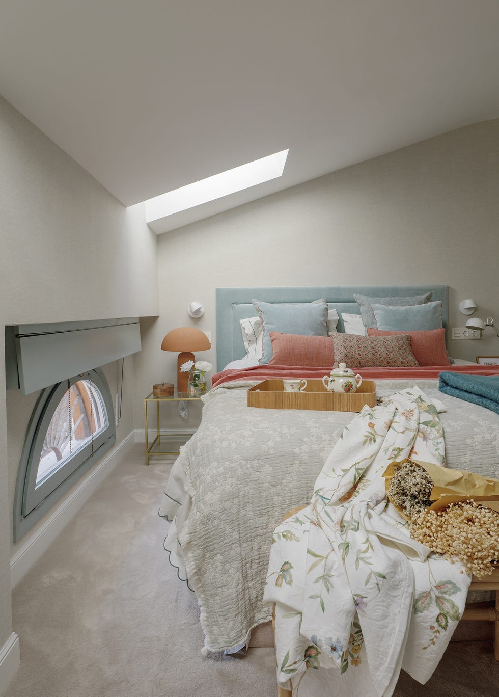dormitorio con cabecero azul y banco de ratán a los pies de la cama