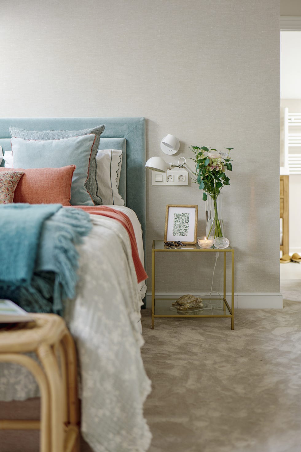 dormitorio con cabecero azul y mesita de latón y cristal