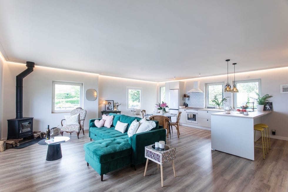 cocina blanca abierta al salón con sofá con chaiselongue de terciopelo verde