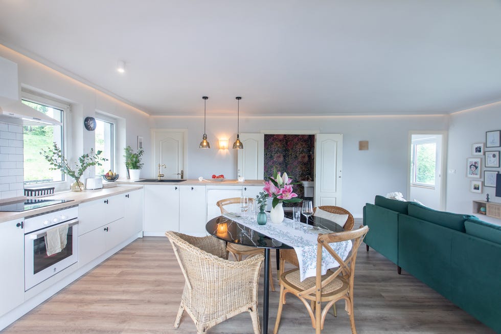 cocina blanca abierta al salón con office y sofá con chaiselongue de terciopelo verde