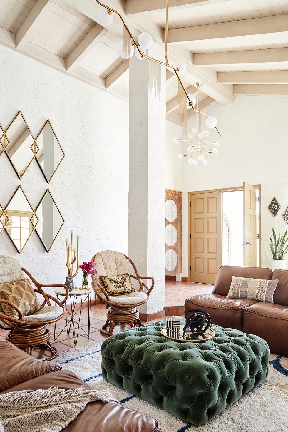 salón con mesa de centro de terciopelo verde, butacas de madera y sofás de piel