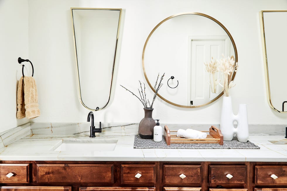 baño con mueble bajo lavabo de madera y espejos con marcos dorados