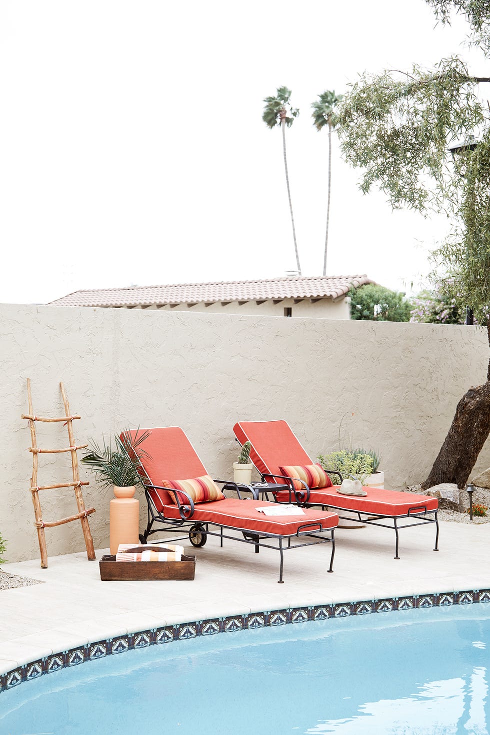 piscina con tumbonas en color coral y decoración de estilo boho