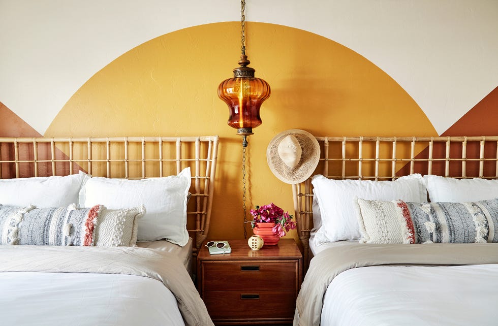 dormitorio con cabeceros de fibras y pared decorada en color mostaza