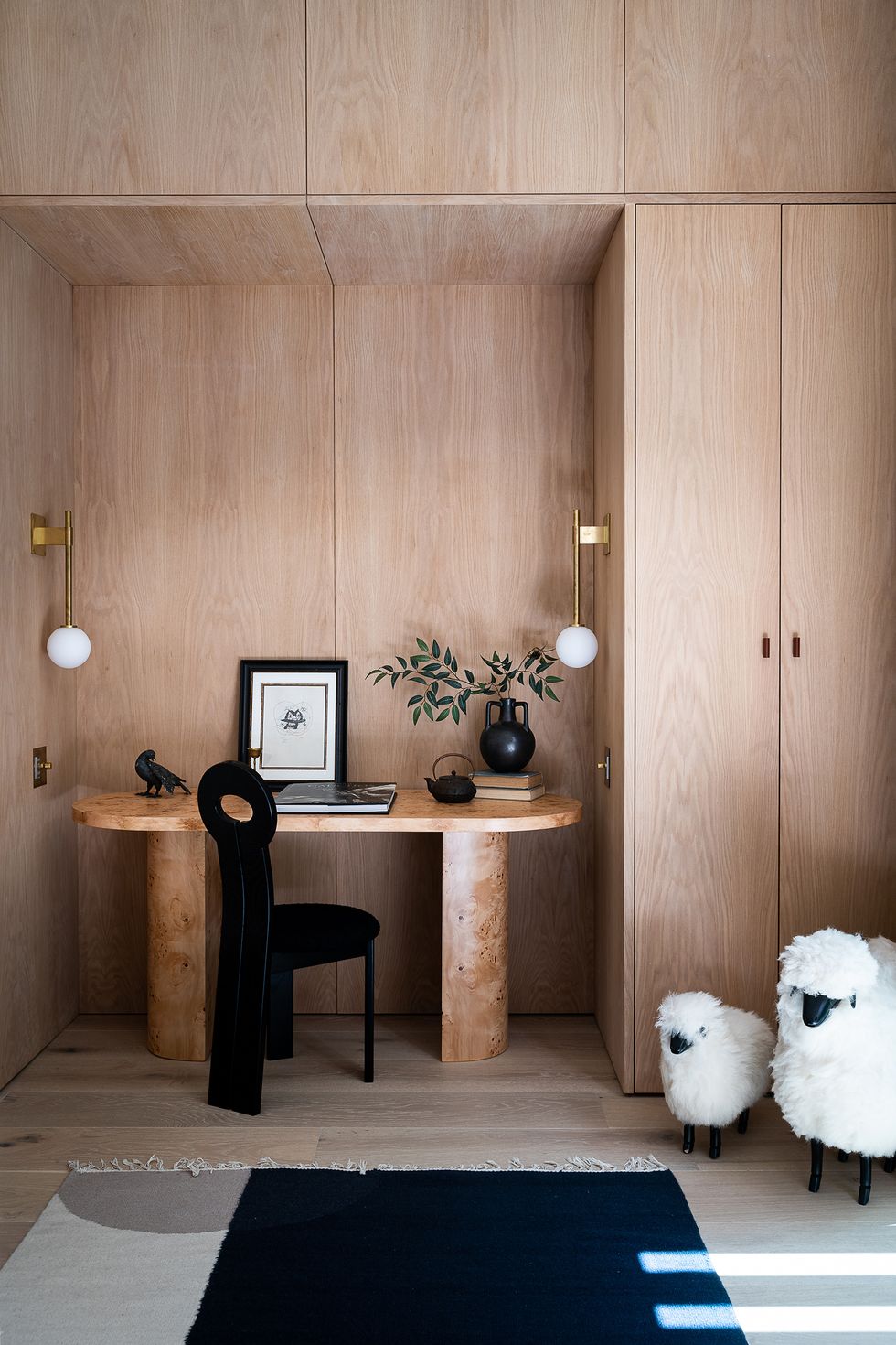 despacho con armario de madera, escritorio ovalado y silla negra de diseño