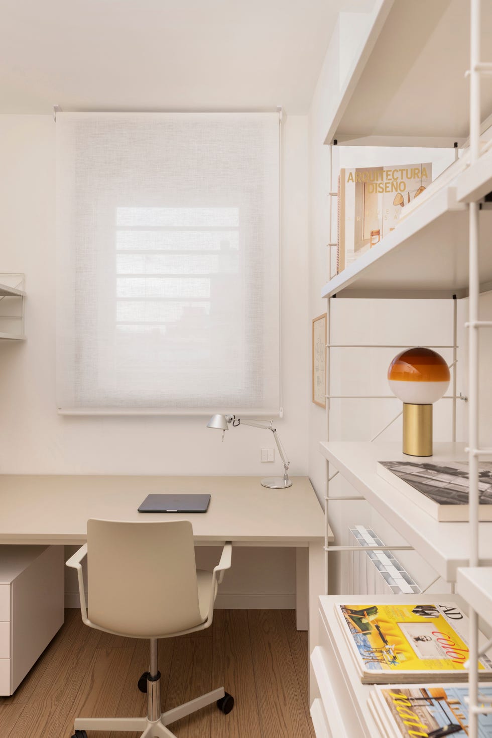 despacho con escritorio y silla beige y estanterías de metal blanco