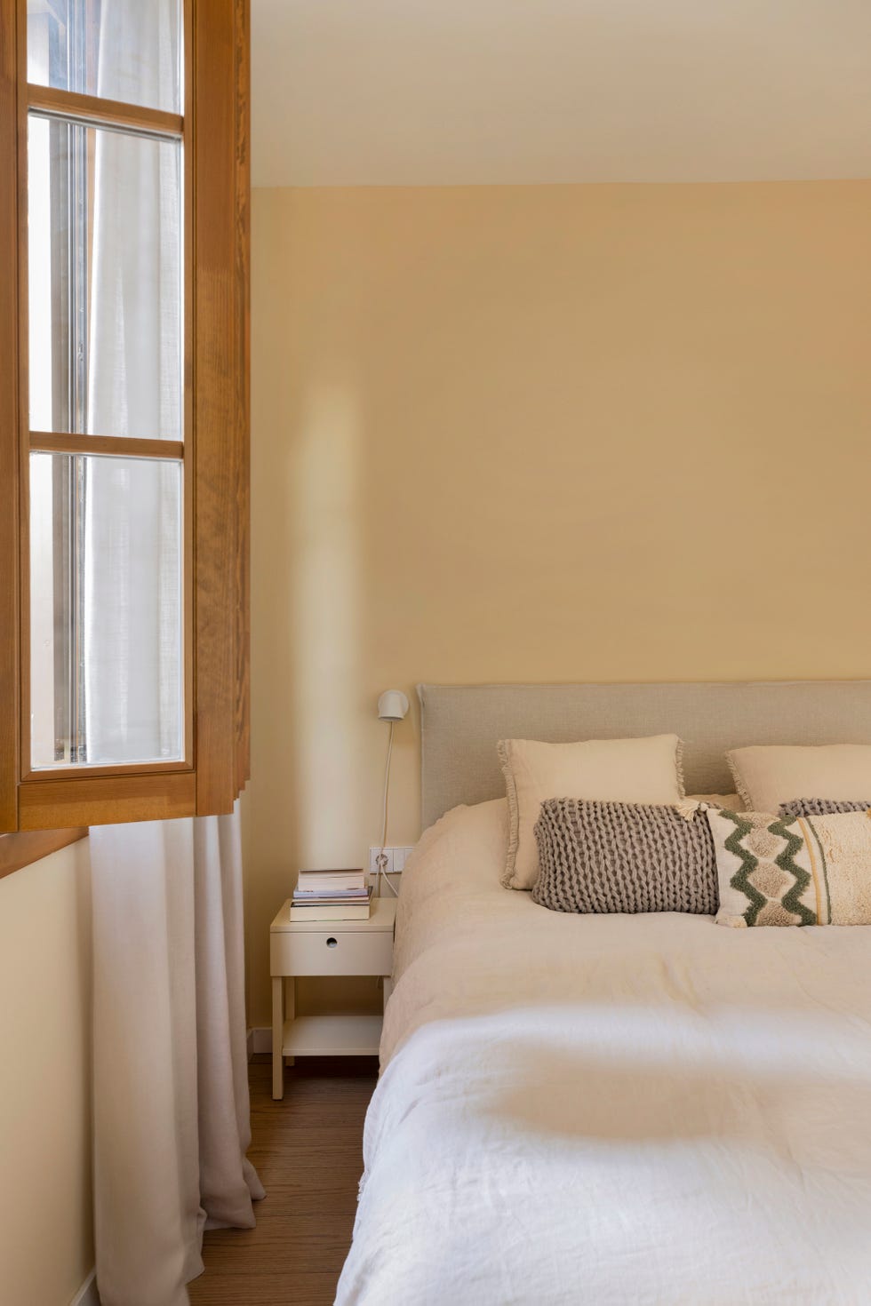 dormitorio con pared en color ocre y cabecero tapizado en gris
