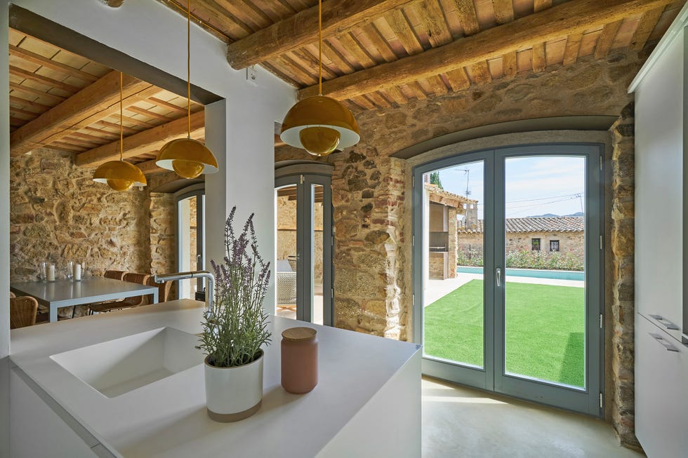 cocina abierta al comedor con vigas de madera vistas y paredes de piedra