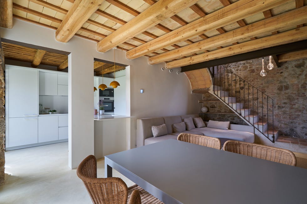 salón comedor abierto a la cocina con paredes de piedra y vigas de madera